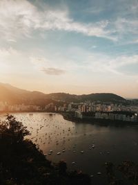 Scenic view of river by city against sky during sunset