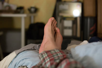 Low section of woman lying on bed at home