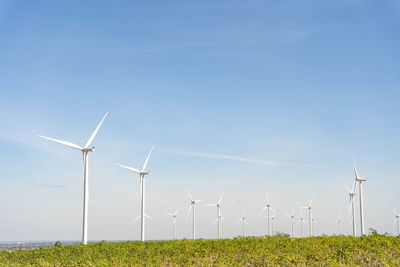 Wind turbines on field against sky