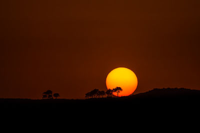 Silhouette landscape against orange sky