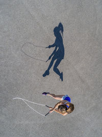 Aerial view of young woman skipping rope, shadow