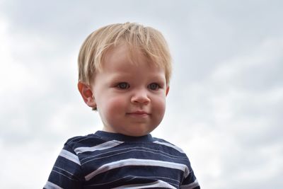 Low angle view of cute smiling baby boy against cloudy sky