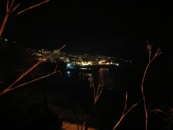 Illuminated cityscape by sea against sky at night