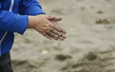 Midsection of child spilling sand