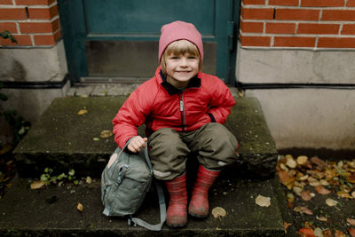 Portrait of smiling boy in warm clothing sitting on steps