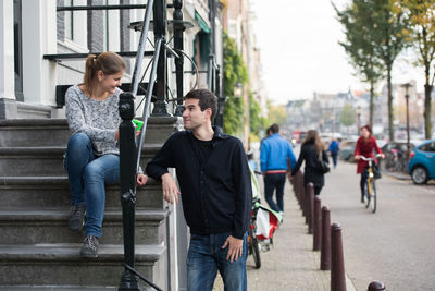 Woman talking with man while sitting on steps