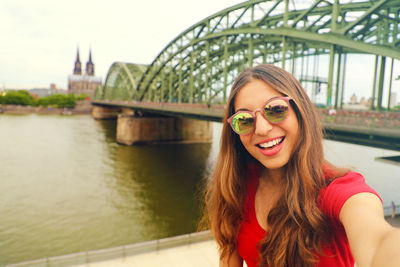 Smiling young woman with hohenzollern bridge over rhine river in background