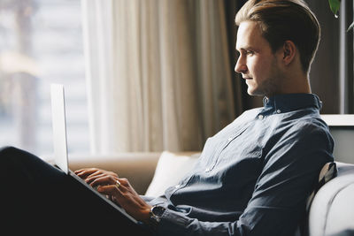 Side view of businessman using laptop at brightly lit office lobby