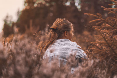 Rear view of woman sitting by plants