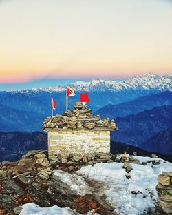 Traditional building by mountains against sky during winter