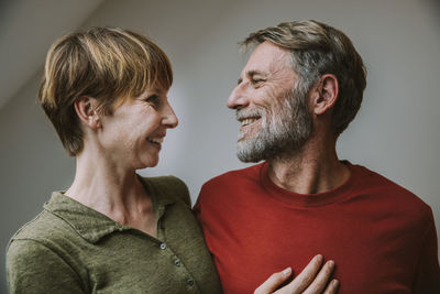 Smiling couple looking at each other while standing at home
