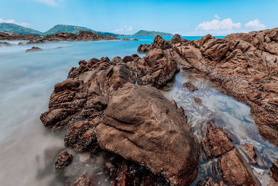 Rock formation on beach against sky