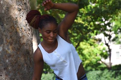 Cute girl standing by tree trunk