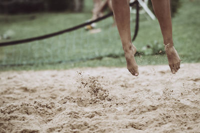 Low section of person jumping on sand