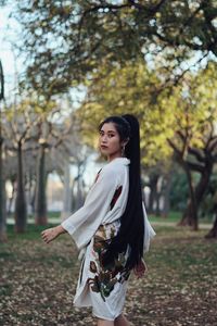 Side view of young woman standing against plants