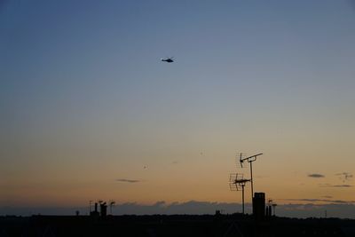 Low angle view of birds flying against clear sky during sunset