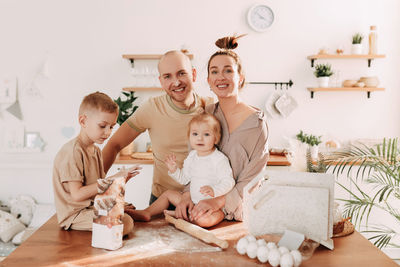 Happy big family of mom dad two kids cooking together and having fun in the kitchen at home