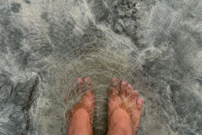 Low section of person standing on sand