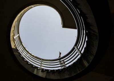 Low angle view of man standing spiral staircase against sky