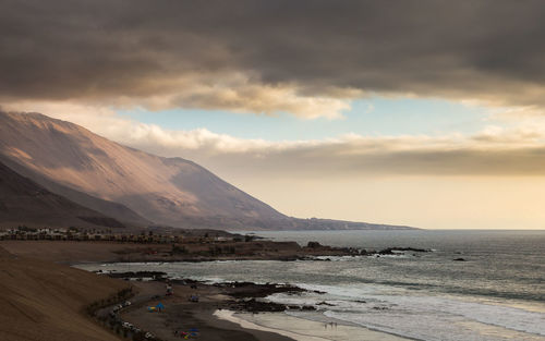 View of calm beach against cloudy sky