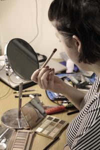 Side view of woman applying make-up on table