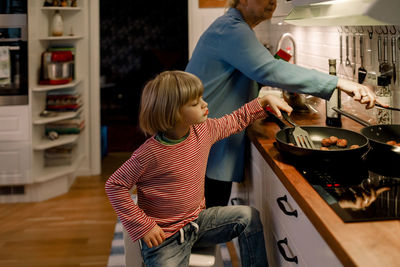 Boy helping grandmother in cooking food at home