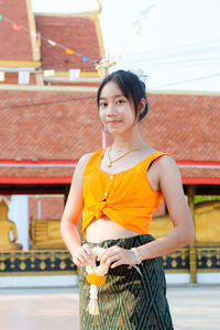 Portrait of young woman standing against wall