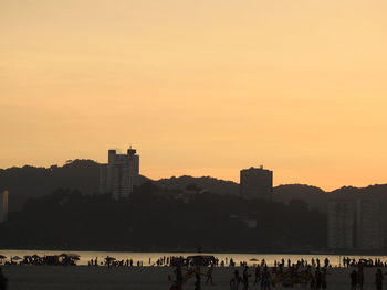 Silhouette people on buildings against sky during sunset