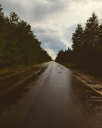 Country road amidst trees against sky