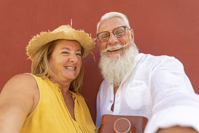 Mature couple standing against red background