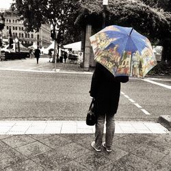 Woman standing on footpath in city