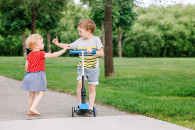 Siblings fighting for fight scooter on road at park