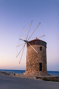 Traditional windmill by sea against clear sky