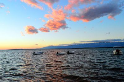 Boats in sea at sunset