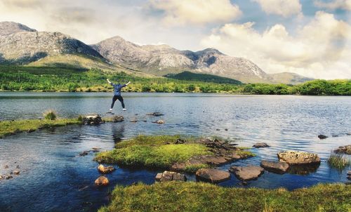 Man jumping from happiness at lough inagh with mountains in the background at connemara, ireland 