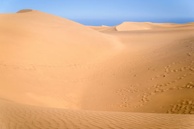 Sand dunes in desert against clear sky