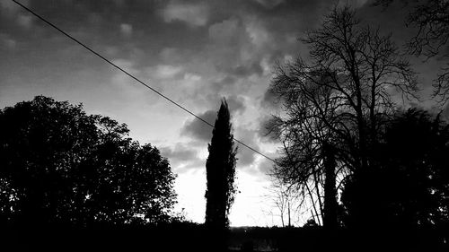 Low angle view of silhouette trees against cloudy sky