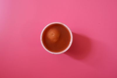 Close-up of coffee cup against pink background