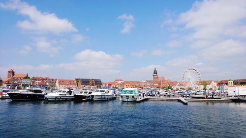 Boats moored by buildings in city against sky