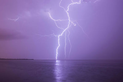 Lightning over sea against dramatic sky