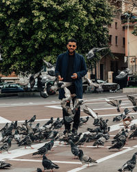 Portrait of young man on road against trees in city