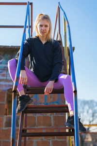 Portrait of smiling woman sitting on slide at playground