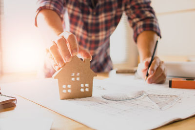 Midsection of man holding paper with toy on table