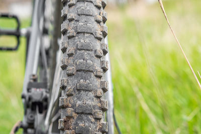 Rear view of a dirty mountain bike wheel that stands against a background of green grass