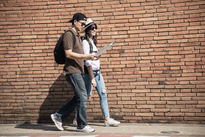 Couple reading map while walking on footpath