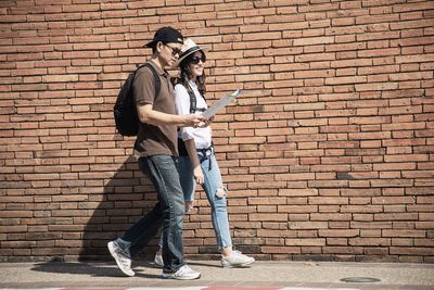 Full length of man standing against brick wall