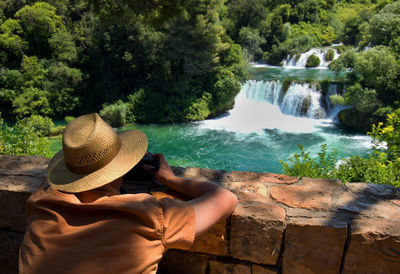 Rear view of man standing by waterfall