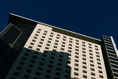 Low angle view of modern building against clear blue sky
