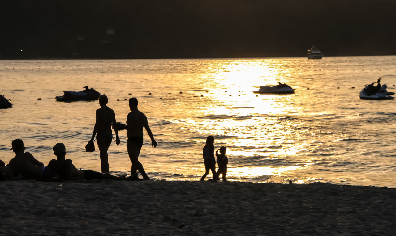 sunset, silhouette, sea, real people, water, beach, leisure activity, nature, lifestyles, beauty in nature, men, horizon over water, outdoors, vacations, scenics, enjoyment, fun, skill, sand, standing, sky, large group of people, togetherness, day, people