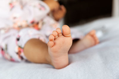 Low section of baby on bed at home